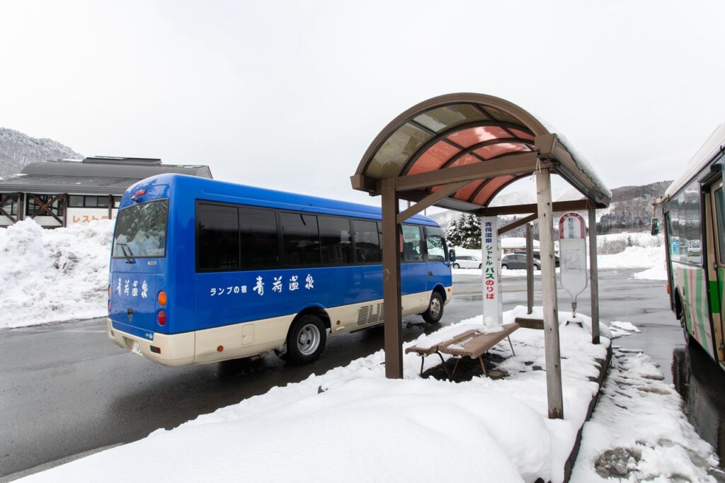 雪景色の中にある青荷温泉の送迎バスが停留所に停まっている様子